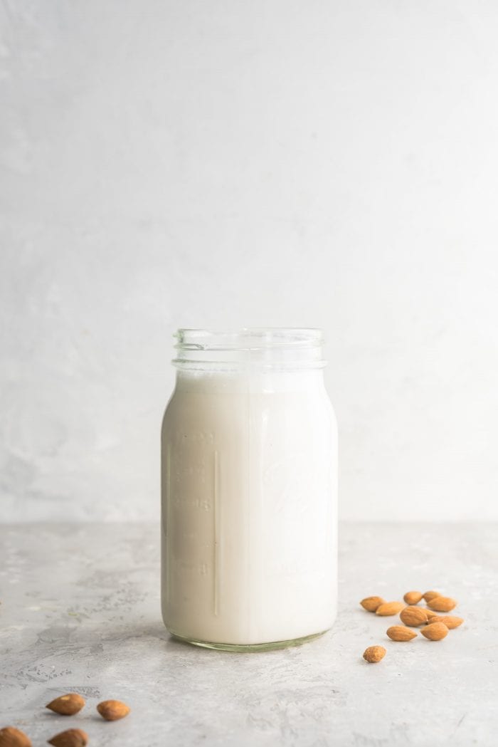 Easy Homemade Almond Milk in a Mason Jar with Almonds Scattered Around