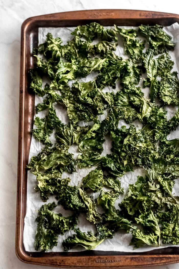Baked kale chips on a baking sheet lined with parchment paper.