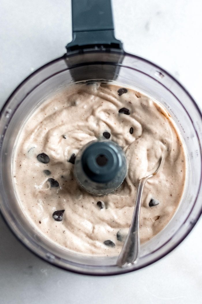 Food processor with blended frozen banana ice cream and chocolate chips.