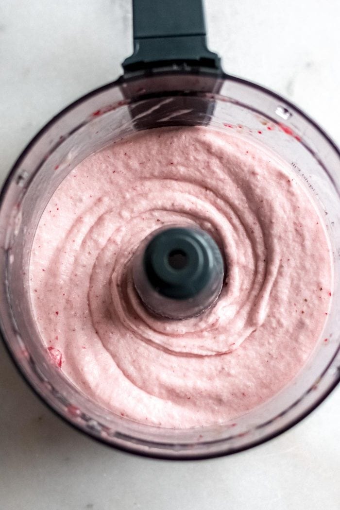 Blended frozen strawberry banana nice cream in a food processor.