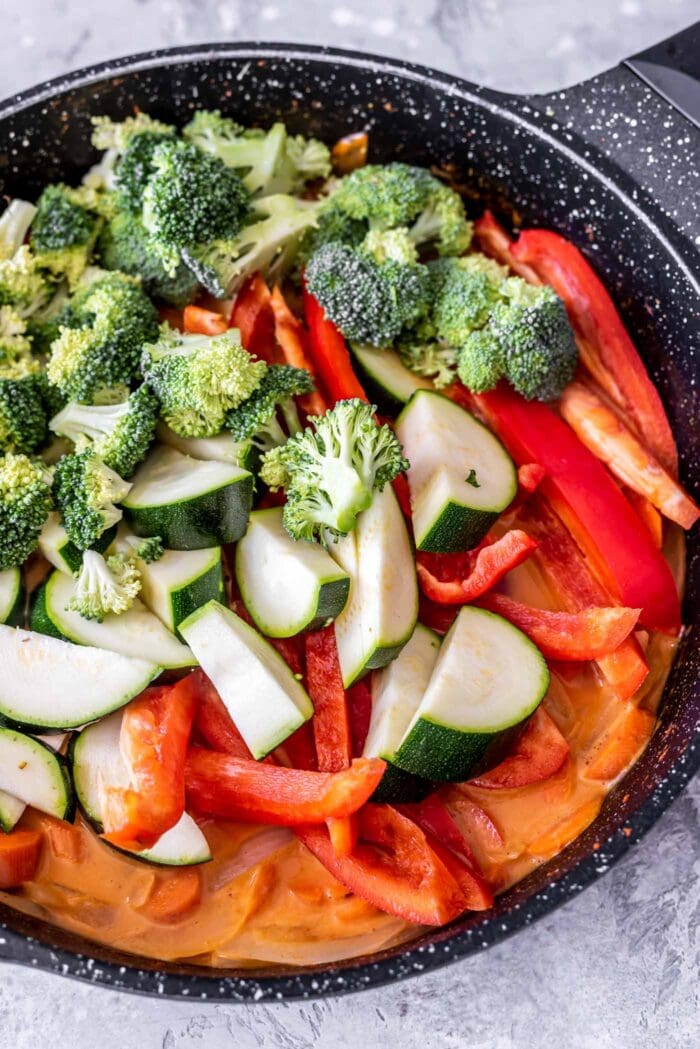 Zucchini, bell pepper, broccoli and carrots in a skillet with red curry sauce.
