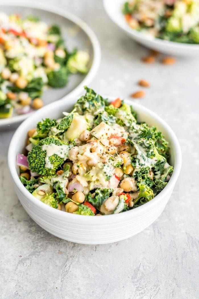 A bowl of chickpea veggie salad with onion, kale, zucchini and bell pepper.