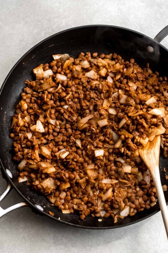 Vegan lentil taco filling in a skillet with a wood spoon.