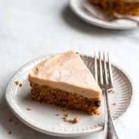 Large slice of raw carrot cake on a white plate with a fork.