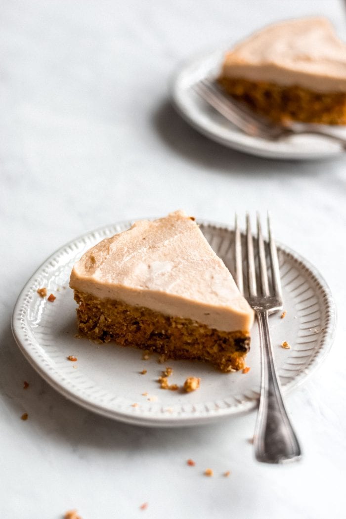 Large slice of raw carrot cake on a white plate with a fork.