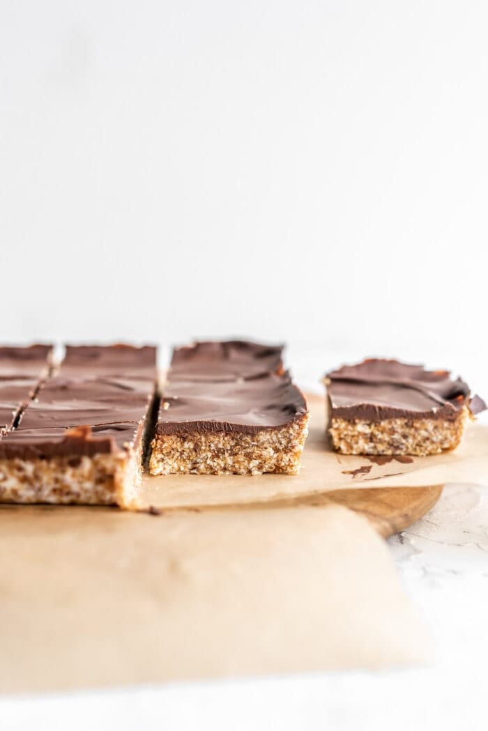 Front on shot of chocolate topped coconut date bars on parchment paper showing the texture of the bars.