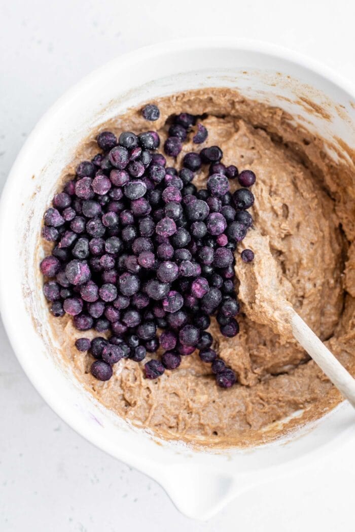 Blueberries being mixed into muffin batter.