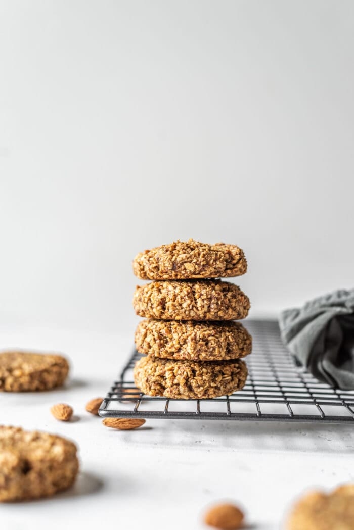 Stack of gluten-free vegan coconut almond date cookies sitting on a cooling rack.