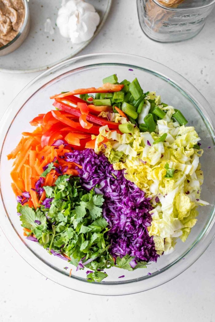 Chopped scallions, cabbage, carrot and cilantro in a large mixing bowl.