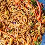 A peanut noodle salad with chopped vegetables in a large mixing bowl.