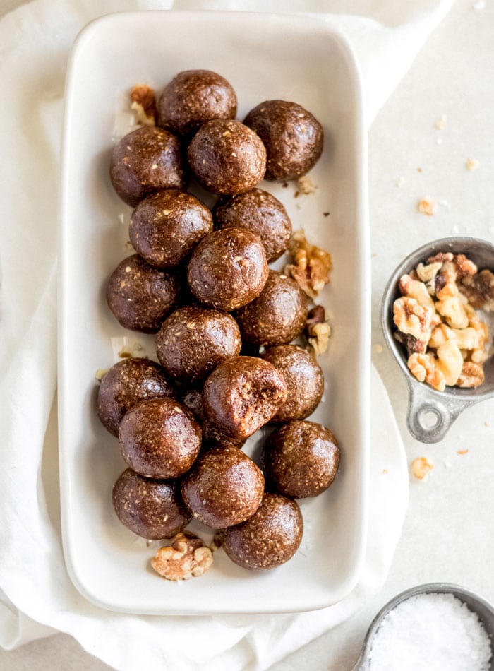 A plate of gingerbread balls, one on top has a bite out of it.