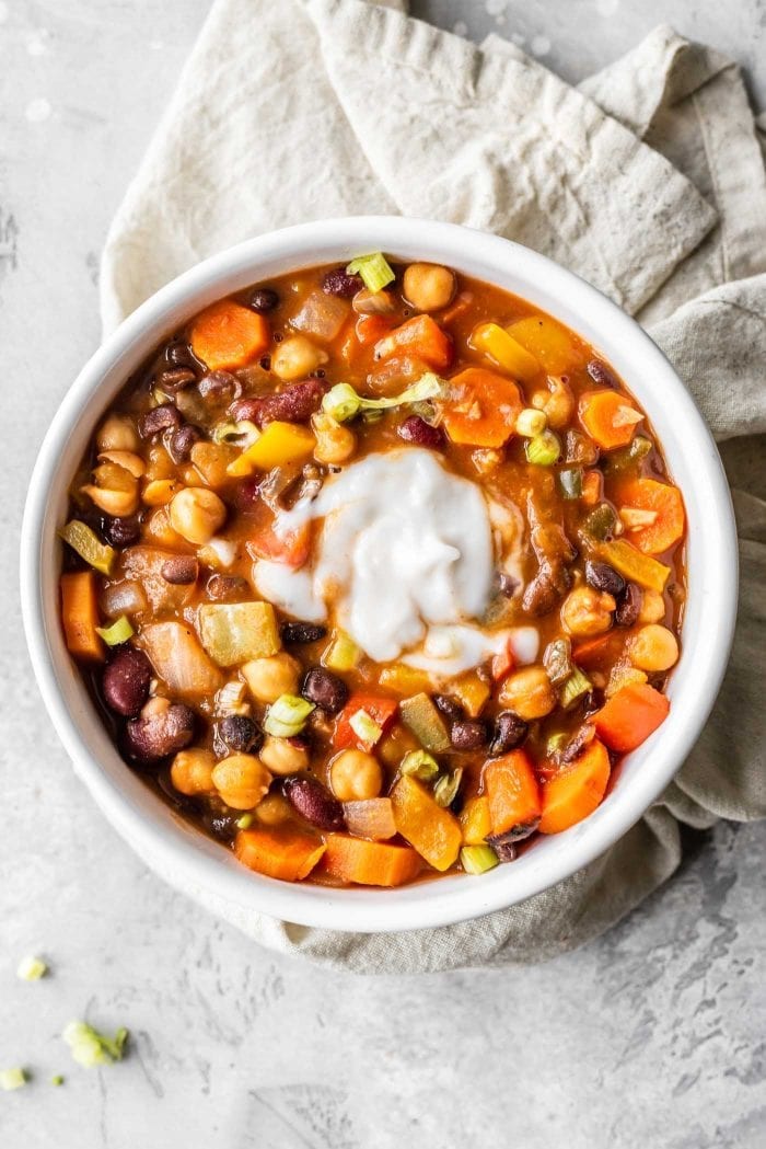 Bowl of vegan 3-bean chili served with green onion and sour cream.