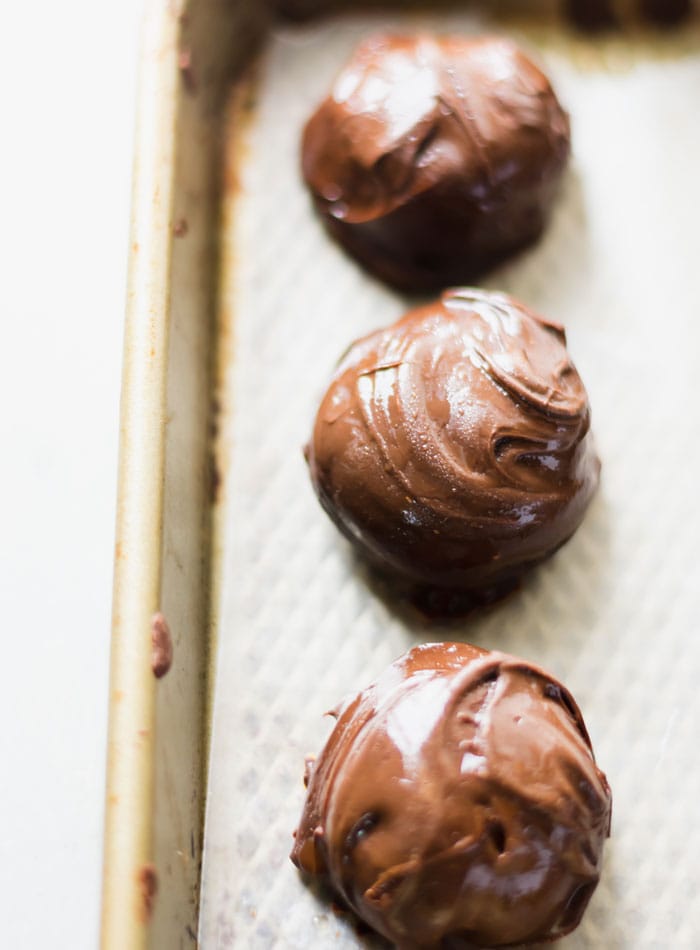 3 chocolate covered peanut butter balls on a baking tray.