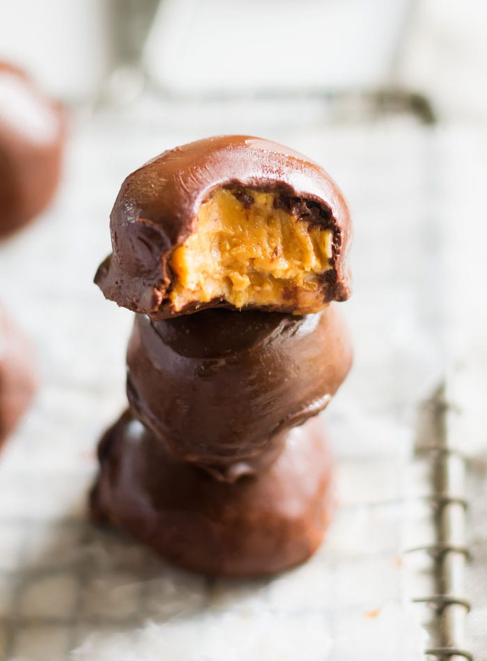 A stack of 3 chocolate peanut butter balls with one on top with a bite out of it.