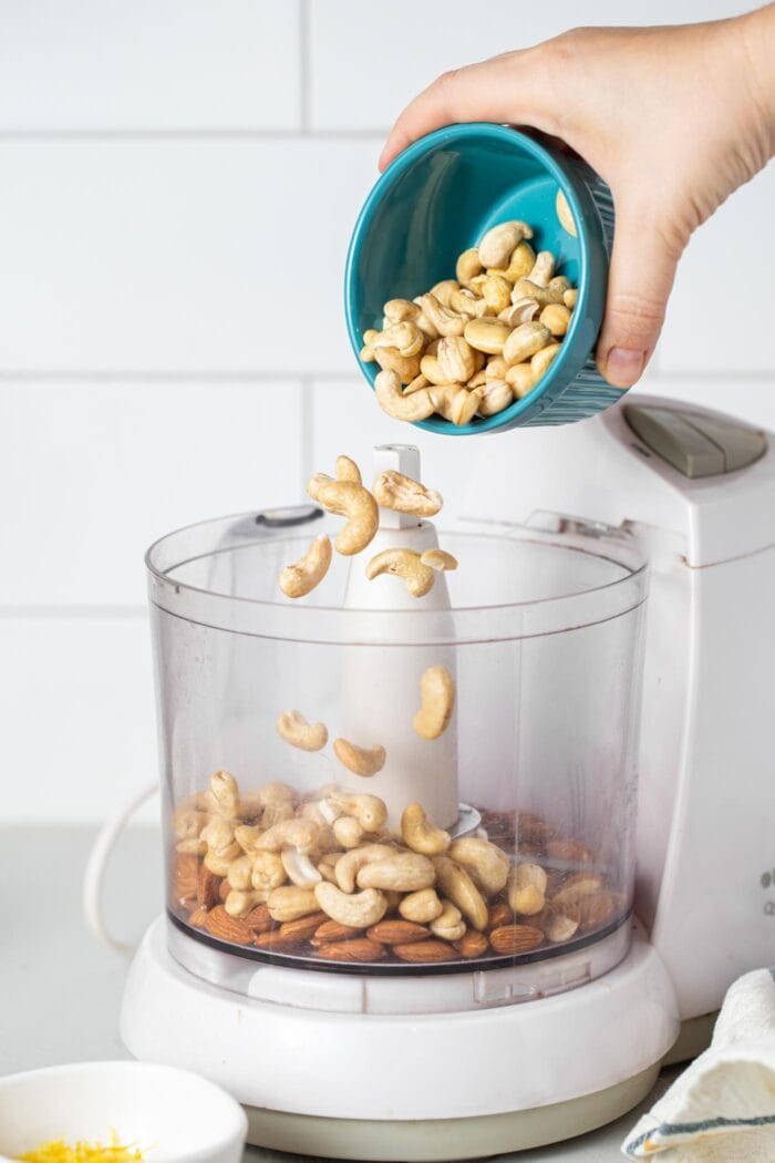 Cashews being dumped into a food processor.