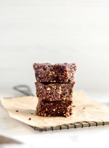 A stack of 3 no-bake coffee brownies on a square of parchment paper on a baking rack.