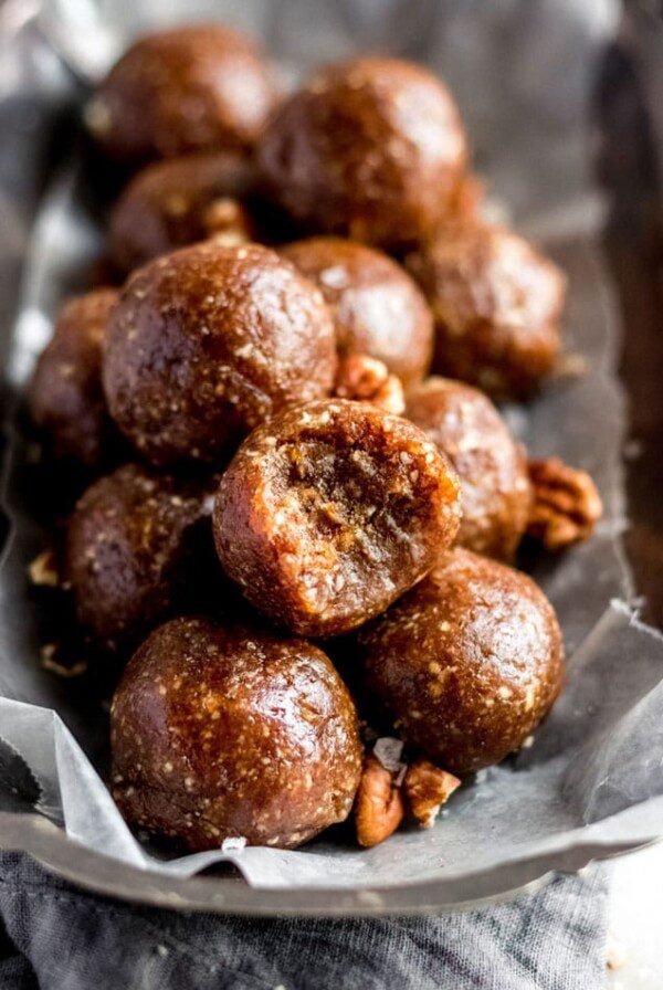 A plate of pecan balls, bite taken out of the one on top.