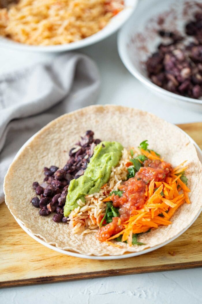 Avocado, rice, black beans and veggies in a large tortilla.