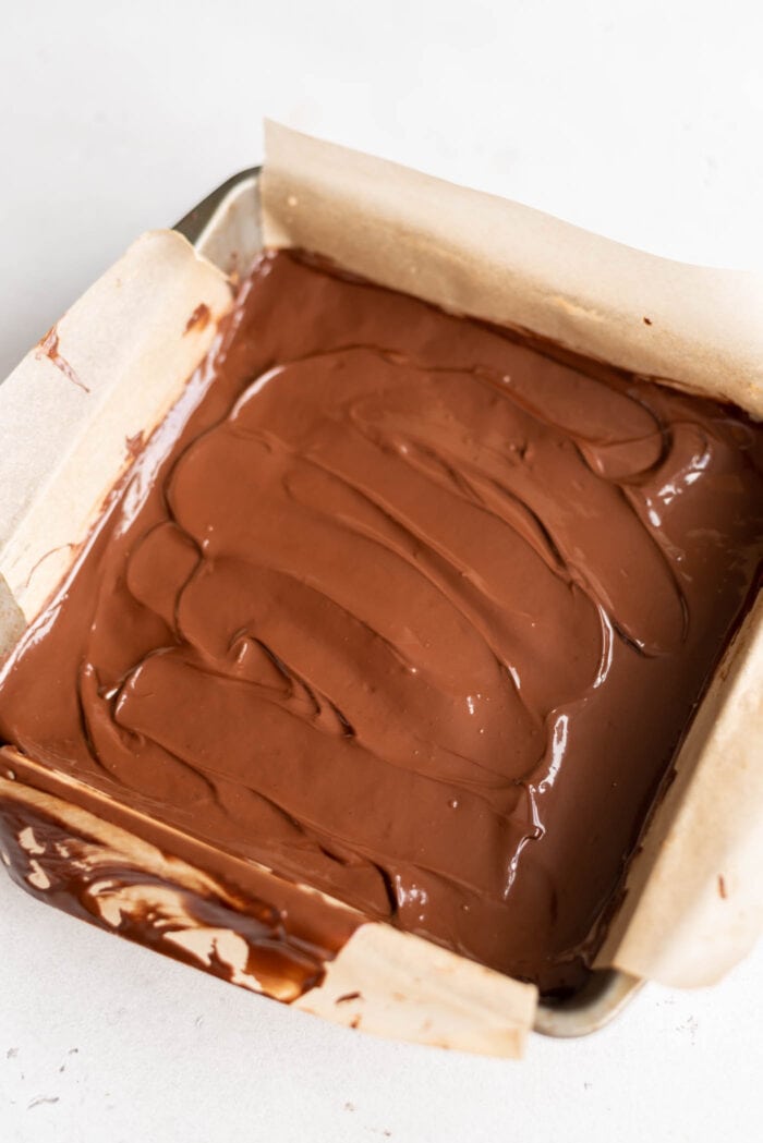 Melted chocolate spread over bars in a small baking pan.