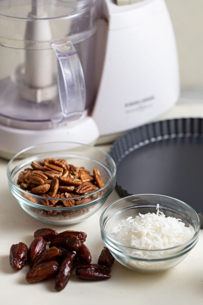 Dates, coconut and pecans in 3 small glass containers.