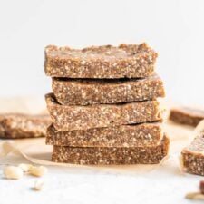 Stack of 5 coconut cashew paleo energy bars sitting on a piece of parchment paper.