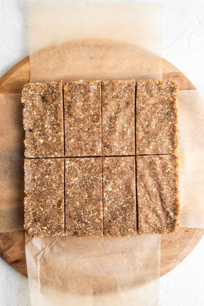 Paleo energy bars with cashews, hemp seeds and coconut sliced into 8 portions on a cutting board.