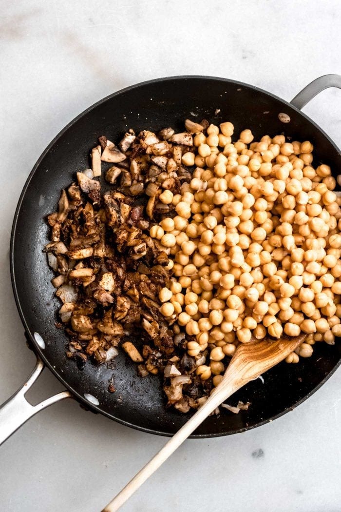 Chickpeas with sautéed mushrooms and garlic in a pan with spices.