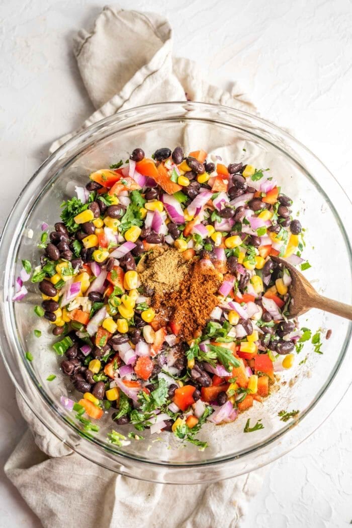 Black bean corn salad with red onion and bell pepper in a glass mixing bowl.