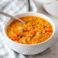 A bowl of red lentil soup on a marble counter top.