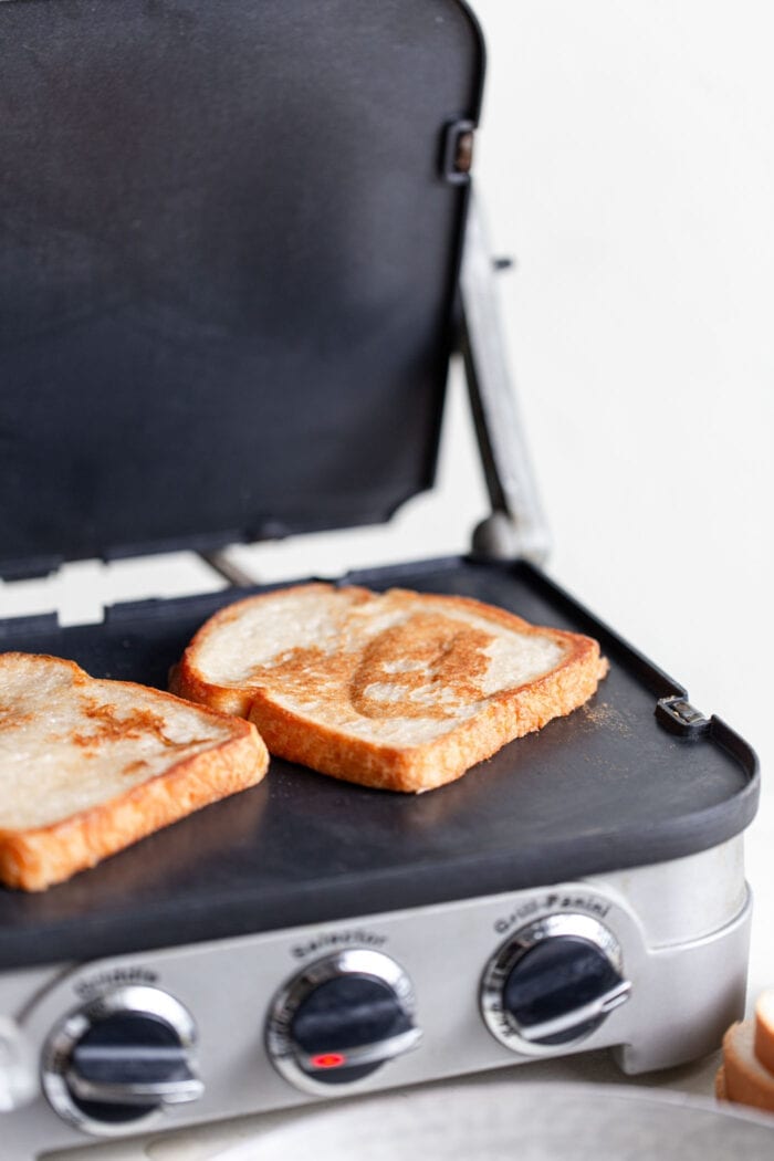 Two slices of fresh toast cooking on a griddle.