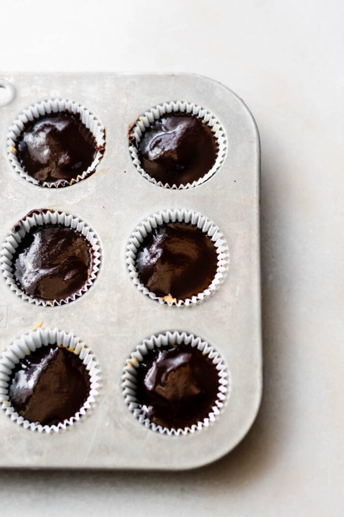 Chocolate filled cups in a lined muffin tin.