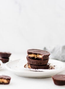 Stack of 3 peanut butter banana cups sitting on a small white plate against a marble background.