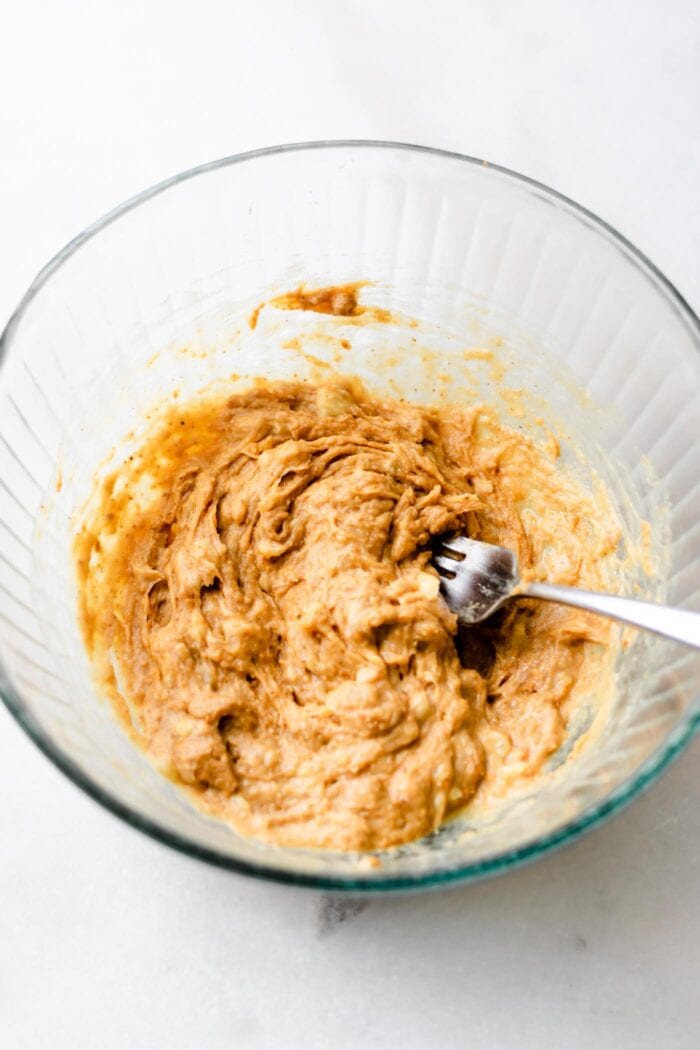 Peanut butter and banana in a glass bowl.