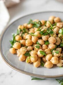 A simple chickpea salad with chopped herbs and garlic on a small plate.