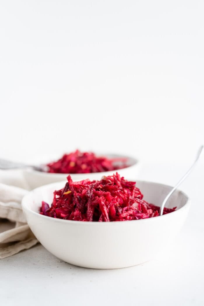 Two bowls of a bright pink beet and apple salad.