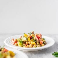 Bell pepper salad with raisins and cucumber on a white plate.