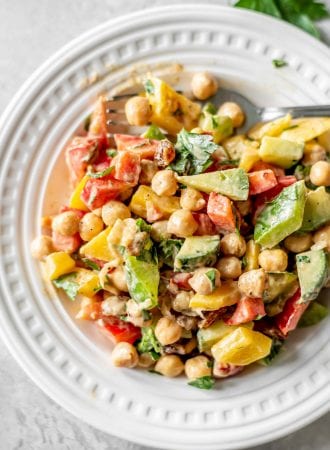 Chopped cucumber and chickpea salad with bell peppers and raisins on a small plate.