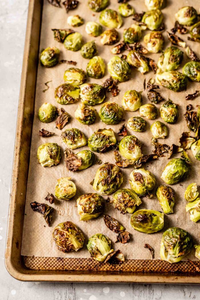 Maple dijon roasted brussel sprouts on a baking tray lined with parchment paper.