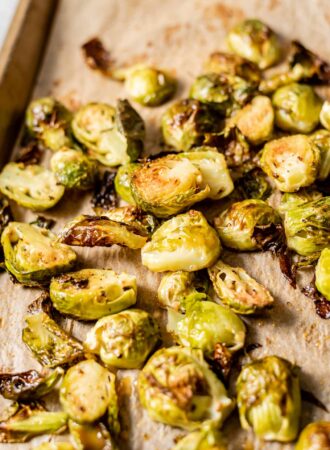 Maple dijon roasted brussel sprouts on a baking tray lined with parchment paper.