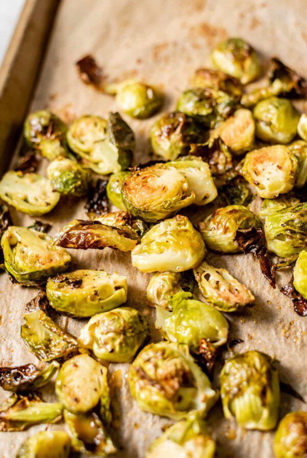 Maple dijon roasted brussel sprouts on a baking tray lined with parchment paper.