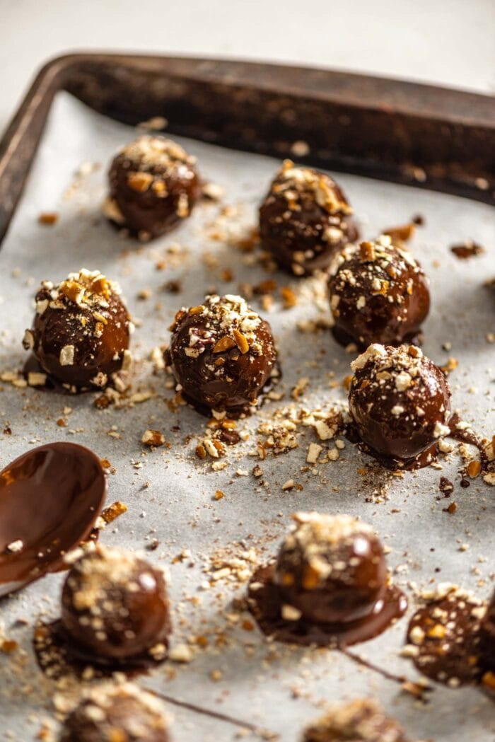 Chocolate covered truffles on a baking tray lined with parchment paper.
