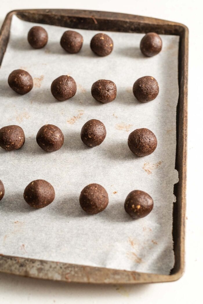 16 chocolate truffles on a baking tray lined with parchment paper.