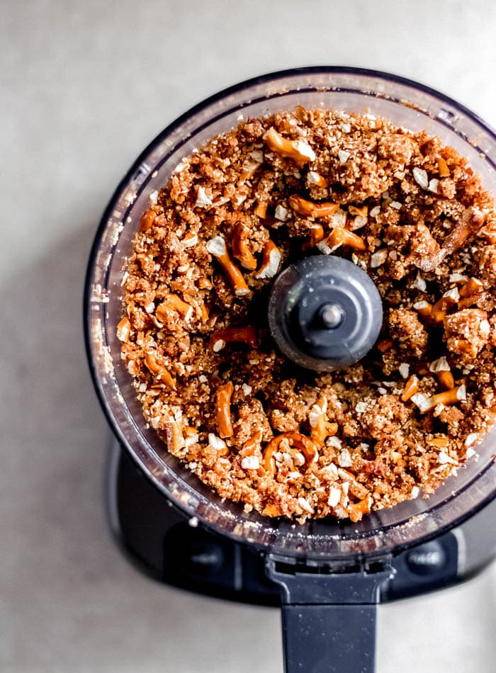 Raw energy bar dough with pretzels mixed into it in a food processor.