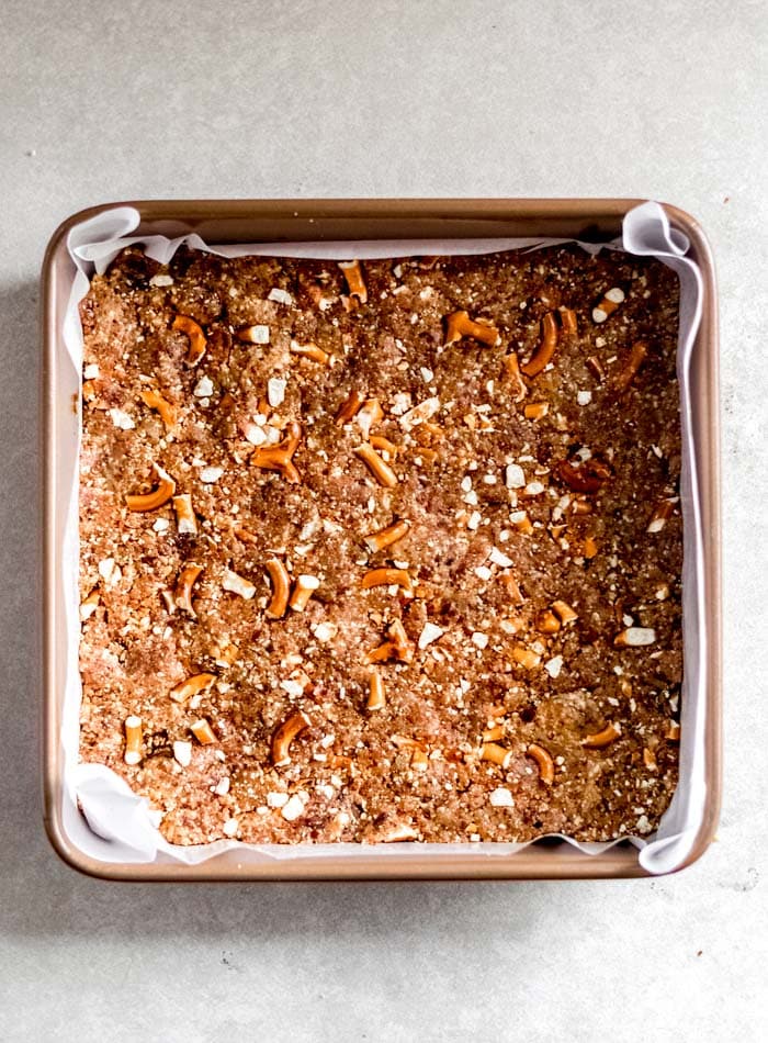Pretzel granola bars in a square pan lined with parchment paper.
