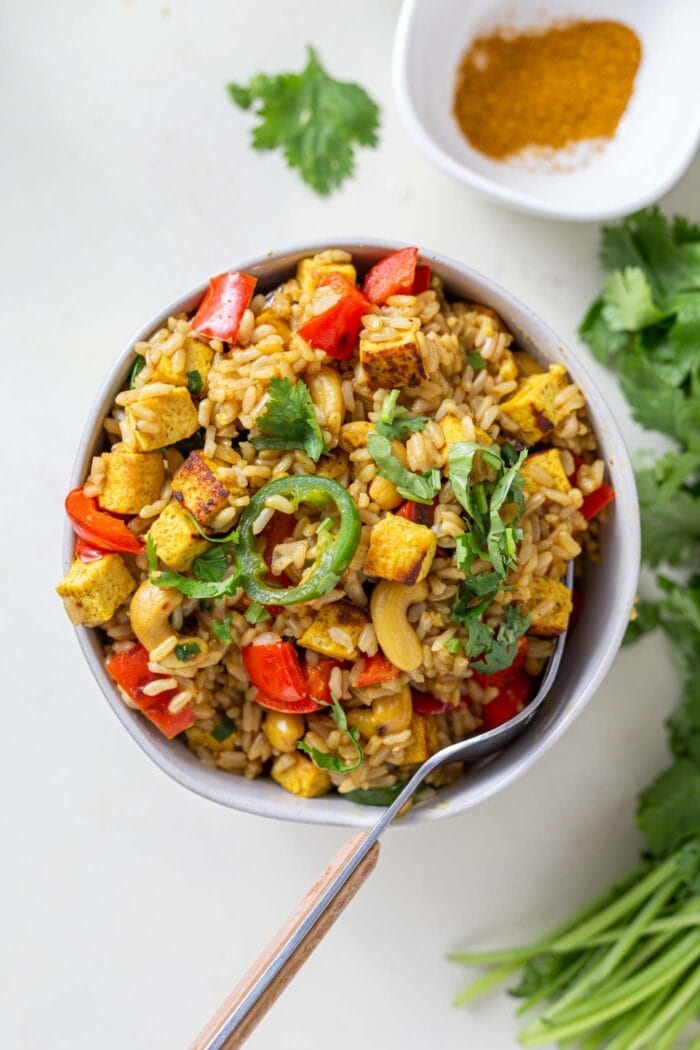 Cashew fried rice with tofu and veggies in a bowl with a fork.