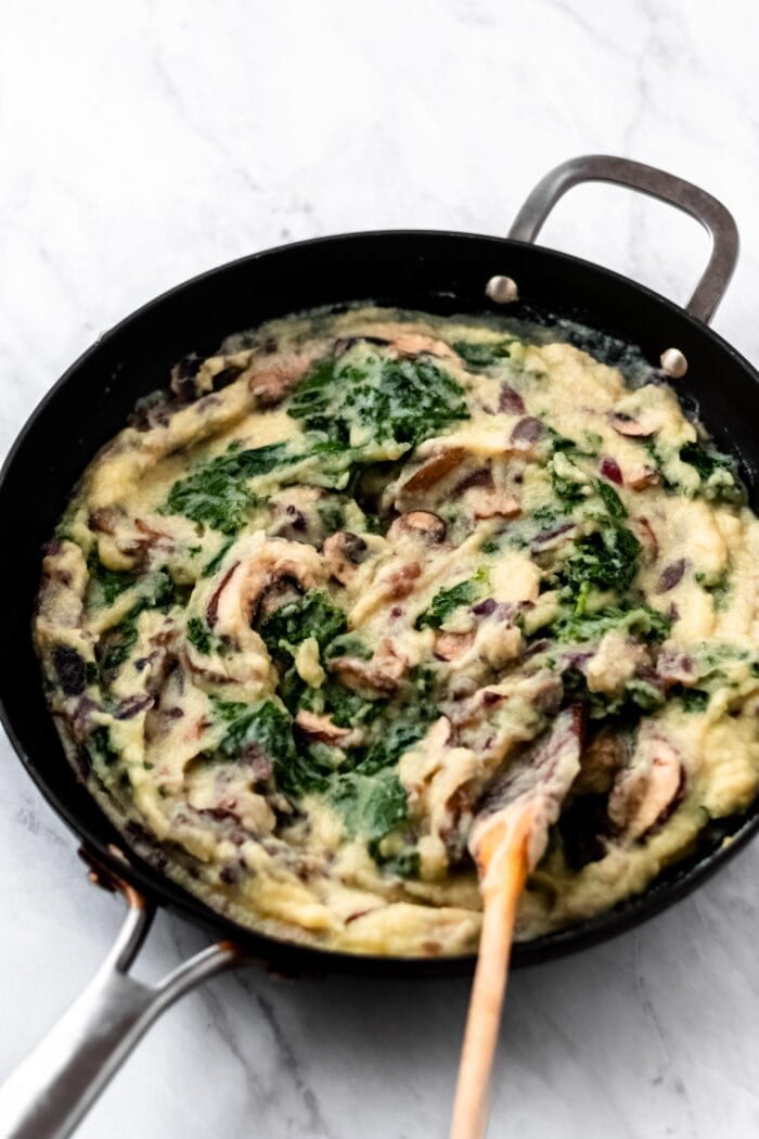 Mashed cauliflower with kale, onions, mushroom and garlic in a large skillet.