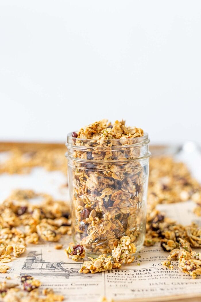 Granola in a glass jar on a baking tray.