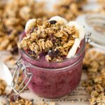 A berry smoothie topped with granola in a jar.