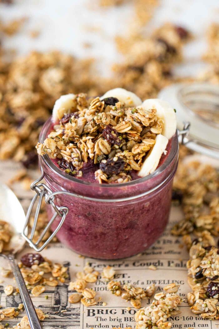 A berry smoothie topped with granola in a jar.