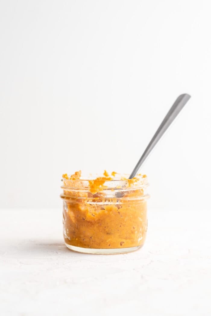 Mashed sweet potato in a small mason jar with a spoon.